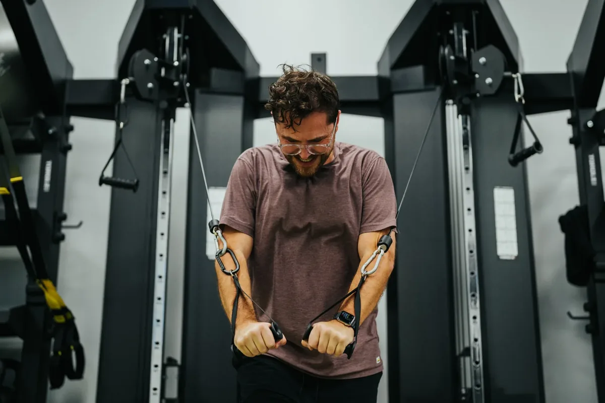 A man works through a cable crossover press during a coached strength interval at an Alloy Personal Training studio