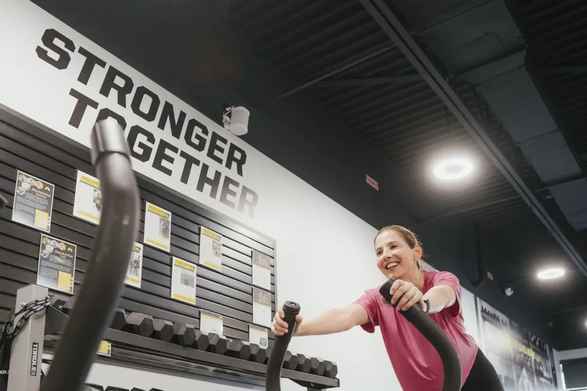 A member drives a weighted training sled across the floor during an off-season strength session at an Alloy Personal Training studio