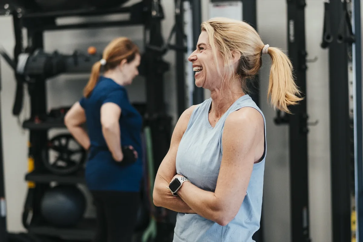 Two members share a laugh between sets at an Alloy Personal Training studio