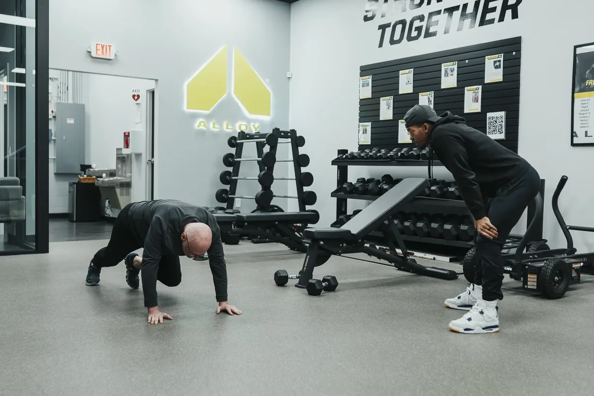 A coach observes a member doing push-ups on the training floor at Alloy Personal Training Middleton in Middleton, WI.