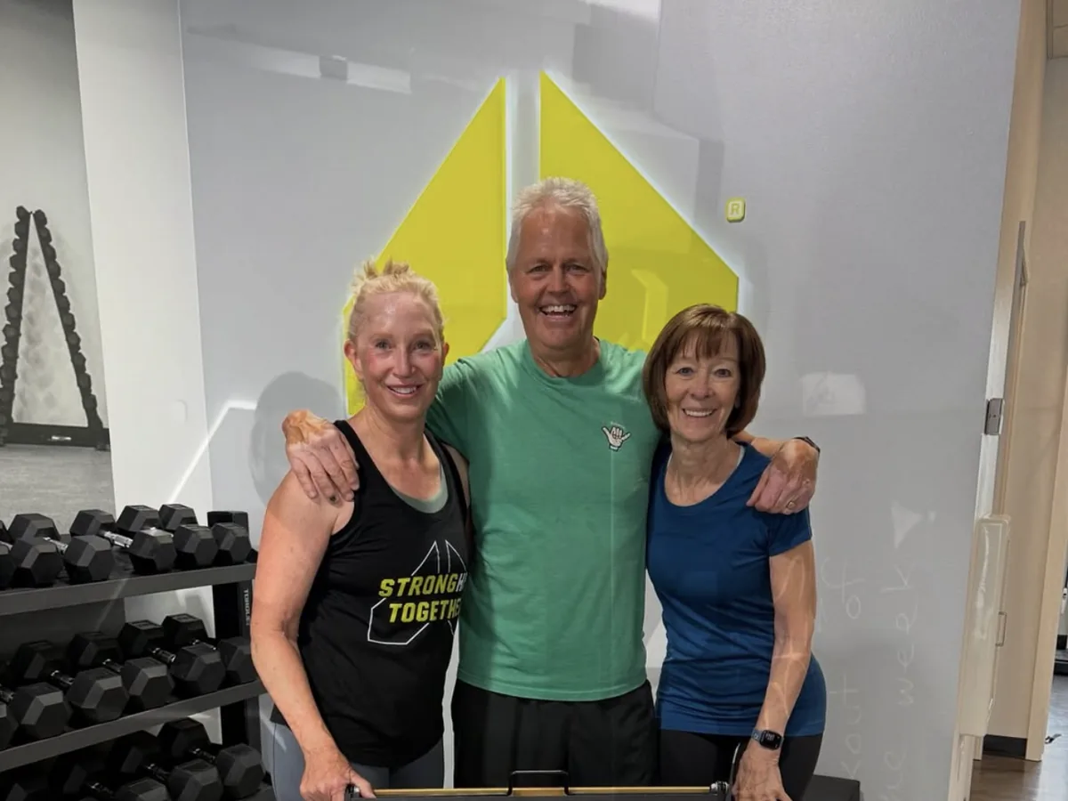 Three Alloy Middleton members arm in arm on the training floor after a workout